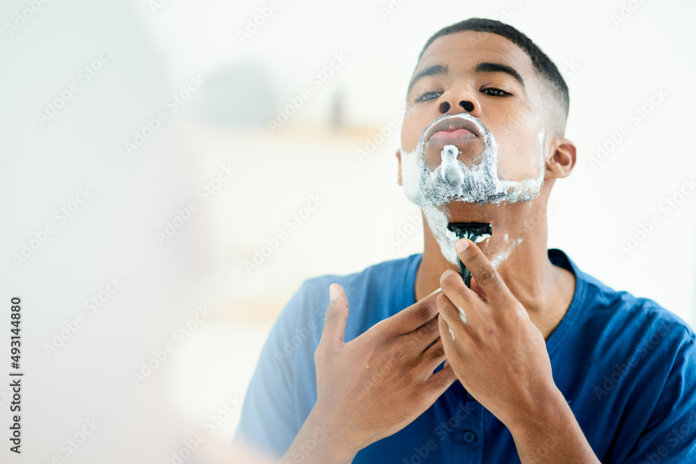 Have to make sure I shave properly this time. Shot of young man focusing on shaving throughly.