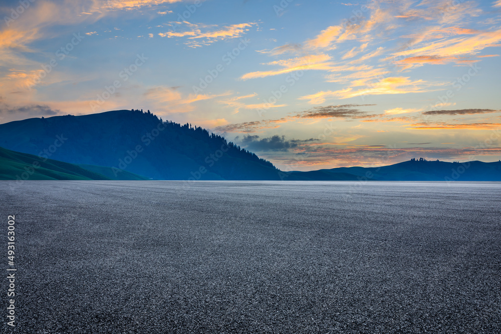 Asphalt road and mountains with beautiful clouds at sunrise