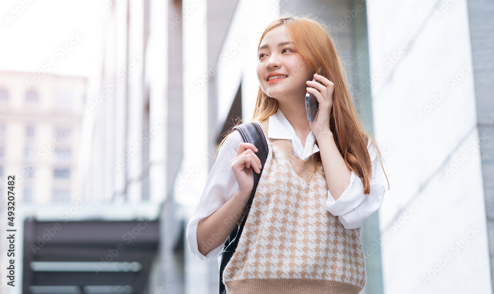 年轻的亚洲女性在街上使用智能手机