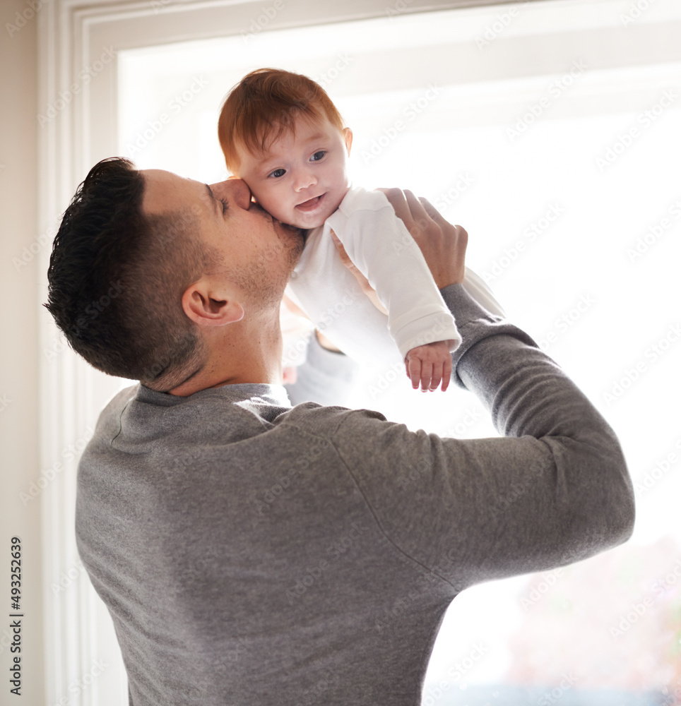 Love at its purest. Shot of a young father holding his adorable baby girl and giving her a kiss.