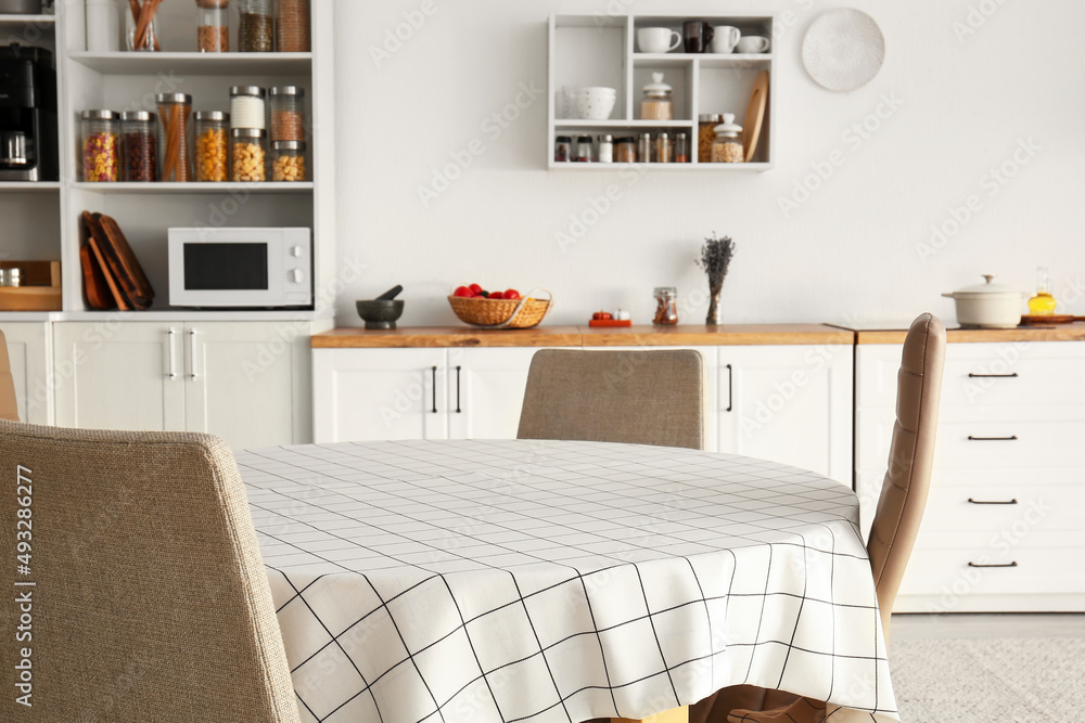 Dining table with cloth and chairs in light kitchen