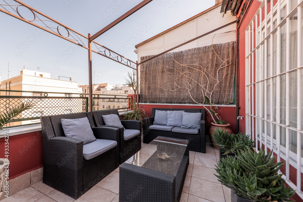 urban terrace of a residential penthouse with plants and wicker furniture with red walls and a gazeb