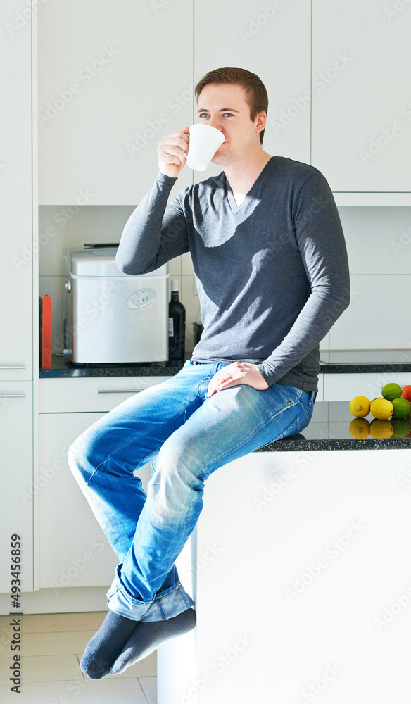 This home runs on laughter and lots of strong coffee. Portrait of a young man sitting on his kitchen