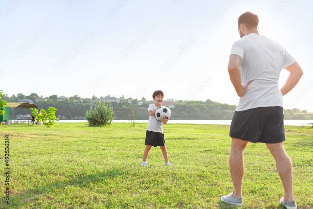 Little boy playing soccer with his father on field