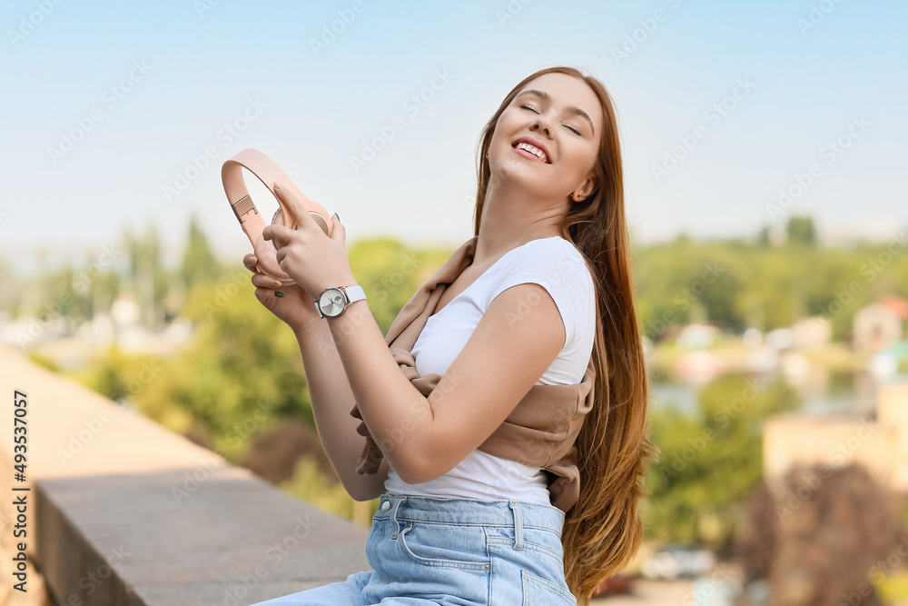 Cool young woman with headphones outdoors