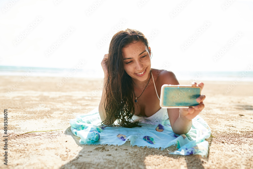 夏季自拍是最好的。一位年轻女子躺在海滩上自拍的照片。