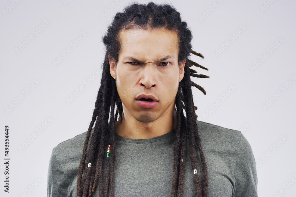 What did you say to me. Studio shot of a young man making a funny face against a gray background.