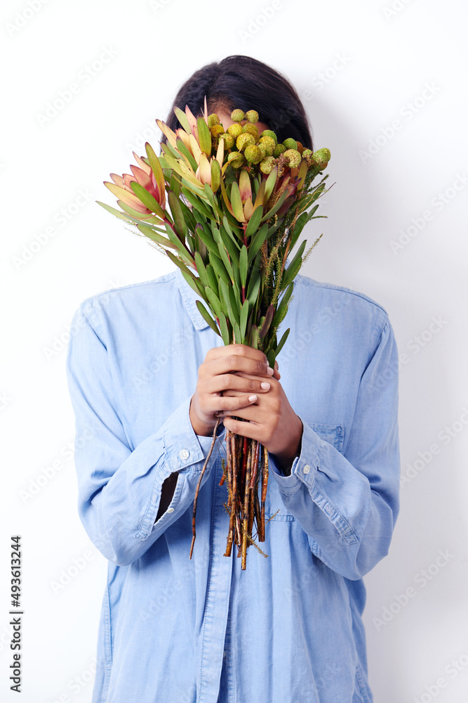 花朵般精致。一位迷人的年轻少数民族女性手持一束鲜花的工作室镜头