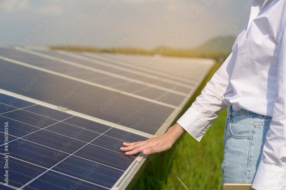 Close up of hand engineer touching with Photovoltaic Cell Farm or Solar Panels Field, eco friendly a