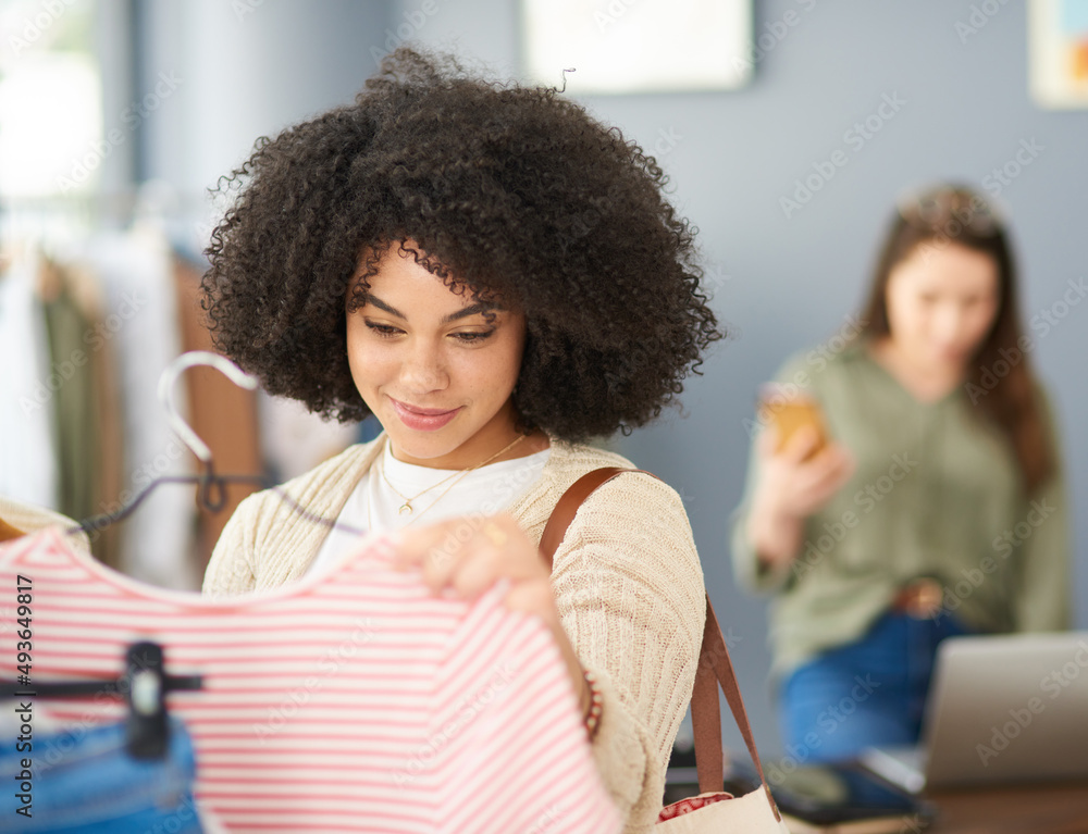 价格标签很有说服力。一个年轻女人在商店买衣服的裁剪镜头。