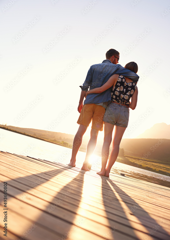 The end to a perfect day together. Rearview shot of an affectionate young couple standing on a dock 