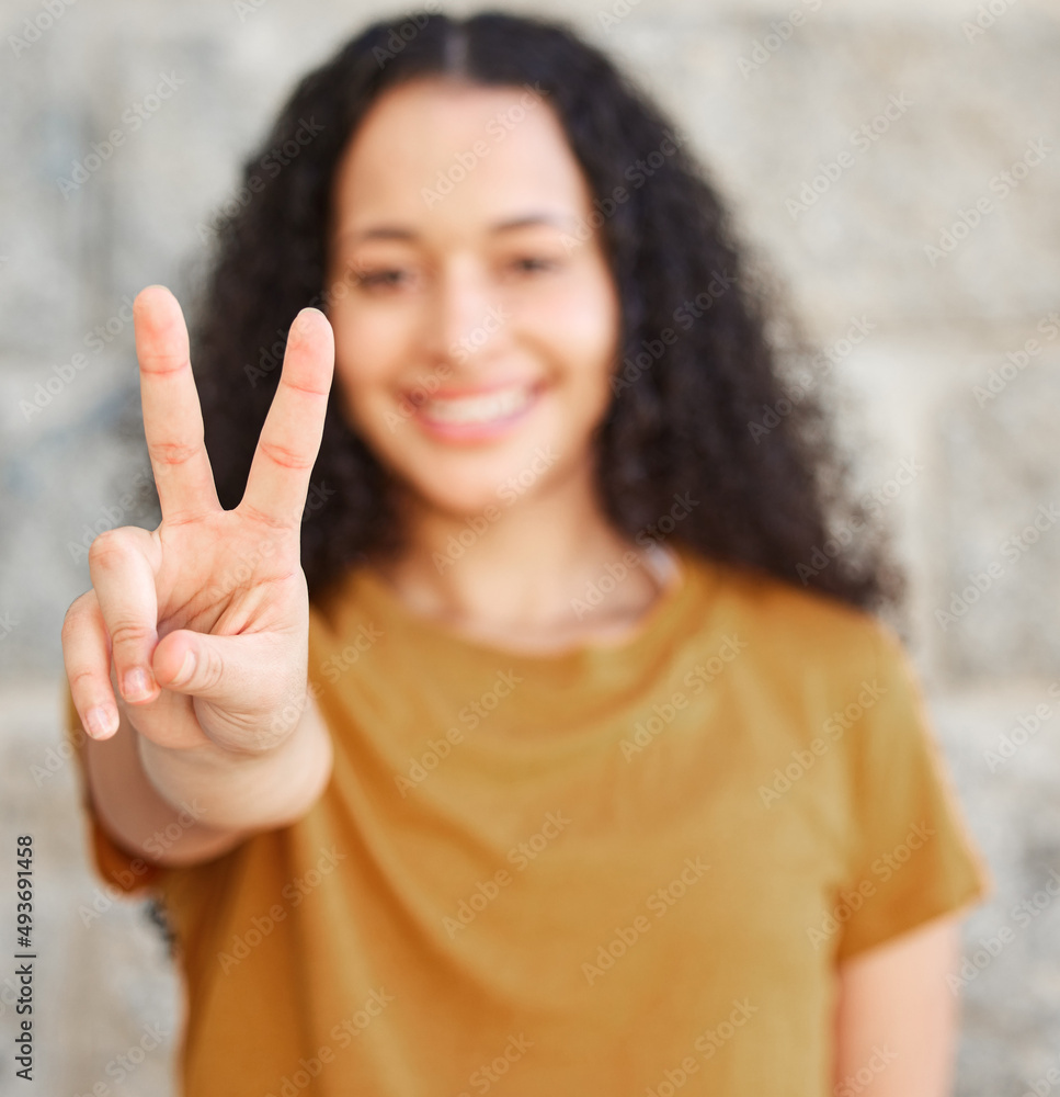 Lets make this world a peaceful one. Shot of a woman showing the peace sign while standing outside.