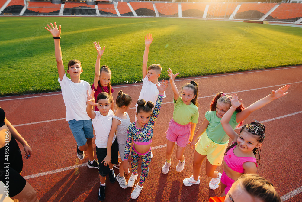 A large group of children, boys and girls, stand together in a circle and fold their hands, tuning u