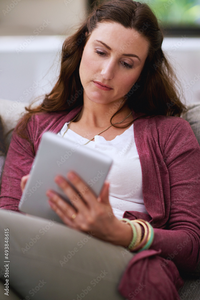 Adding some content to her blog. Cropped shot of a mature woman using her tablet while sitting on th