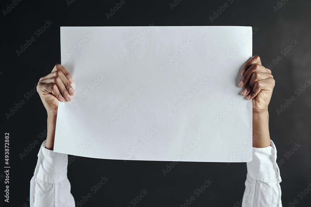 Take a look here. Shot of hands holding up a blank page against a dark background.