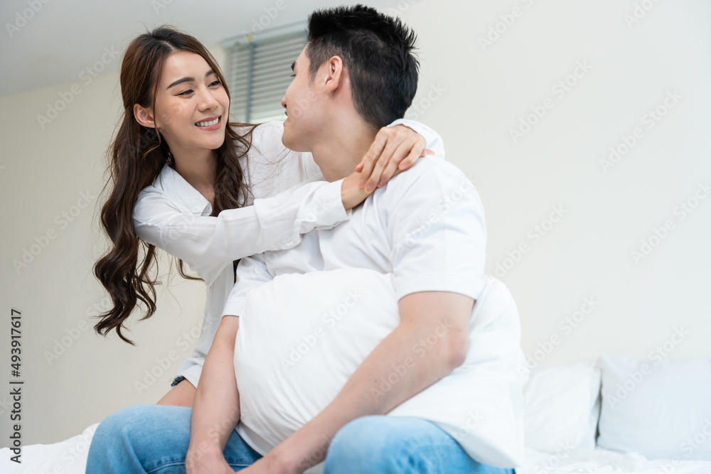 Asian new marriage couple sit on bed and look at each other with love.