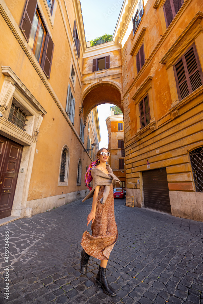 Woman walks on narrow old street with beautiful buildings and arch ahead in Rome. Portrait of a happ