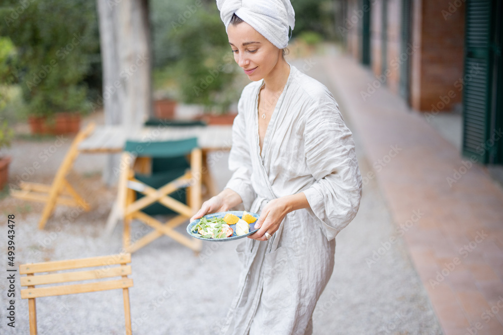 Woman putting a plate with breakfast on a table at hotel terrace at morning time outdoors. Concept o