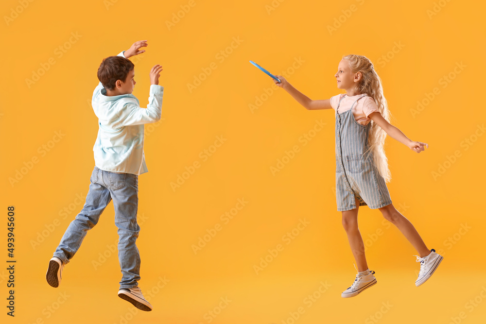 Funny little children playing frisbee on color background