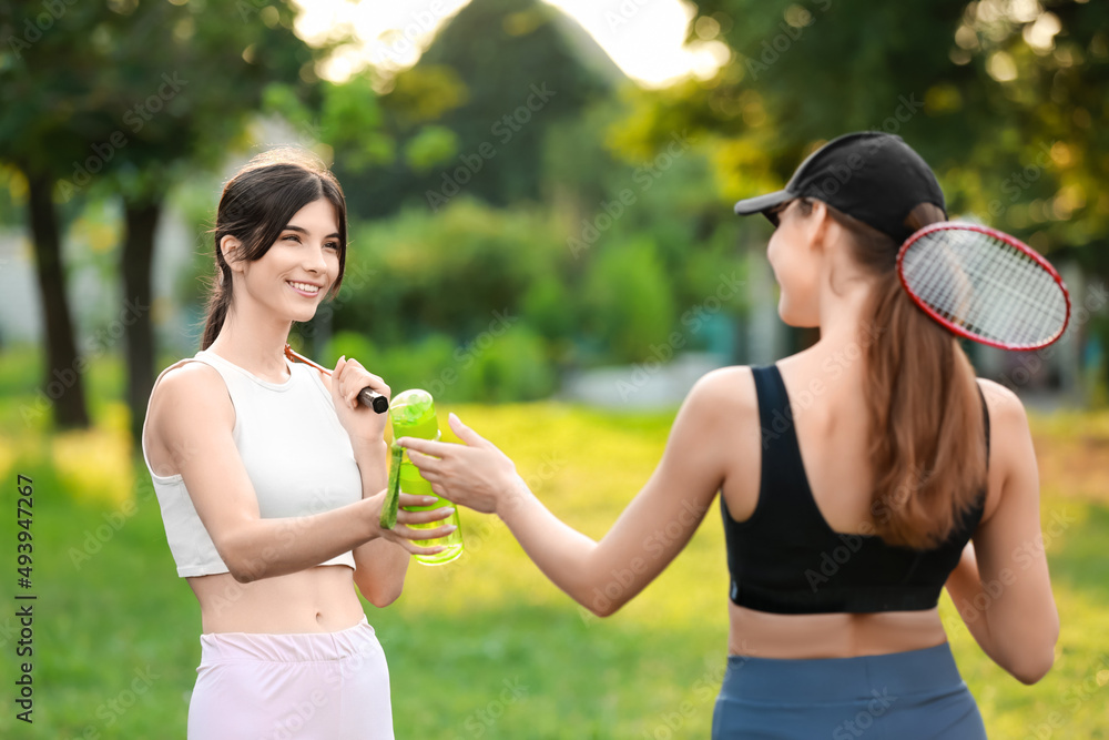 女子羽毛球运动员在户外拿着一瓶水