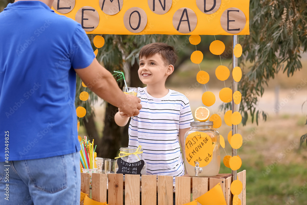 Cute boy selling lemonade in park