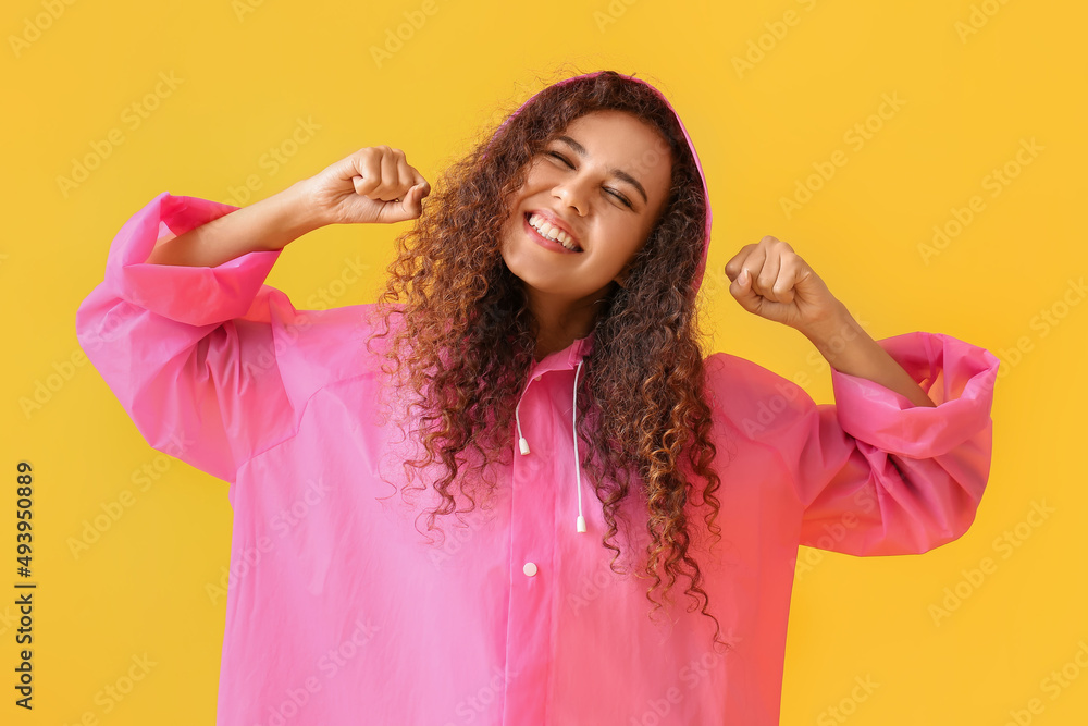 身穿黄色背景粉色雨衣微笑的年轻非裔美国妇女