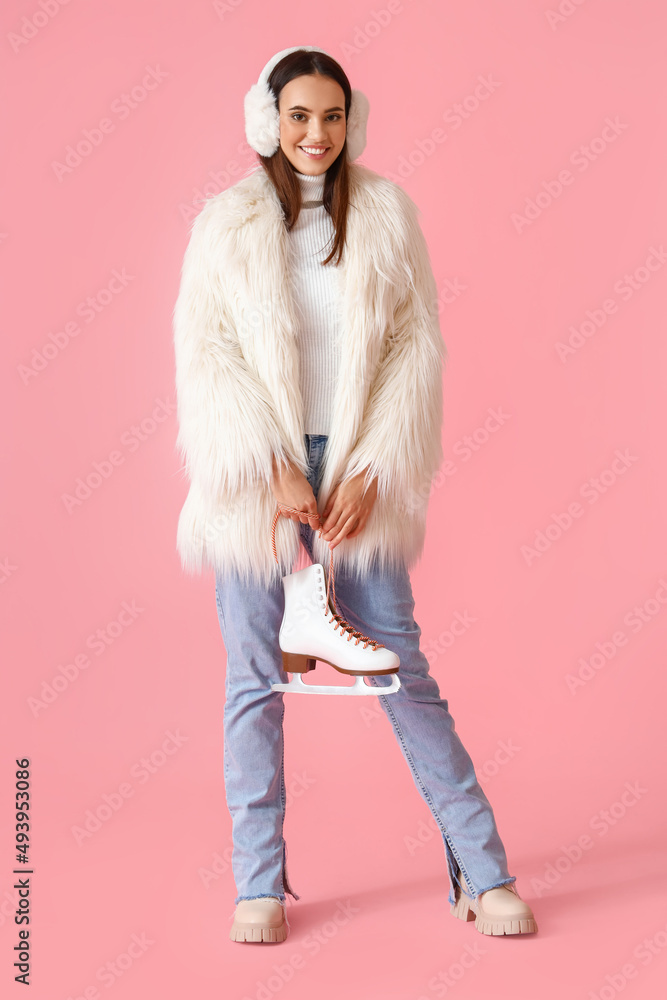 Happy woman in winter clothes and with ice skates on color background