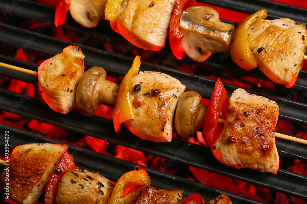 Tasty chicken skewers with vegetables on grill, closeup