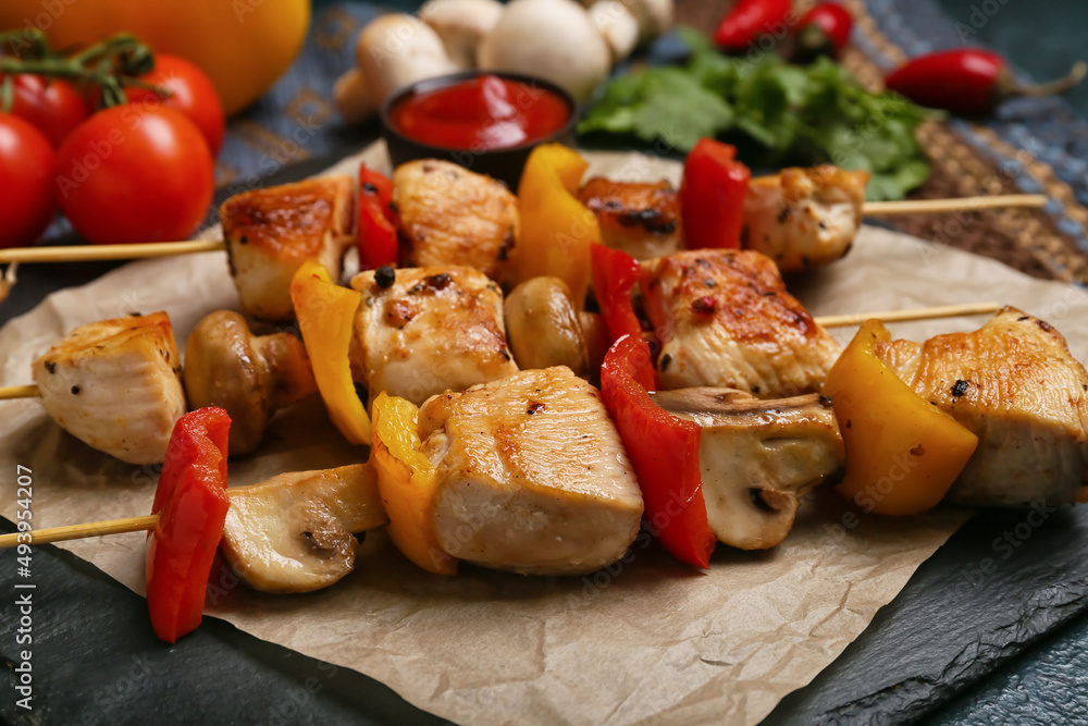 Board of grilled chicken skewers with vegetables on table