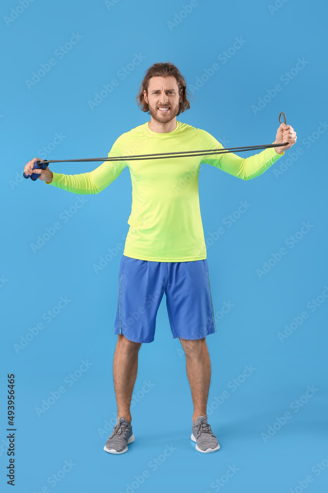 Sporty man with jumping rope on blue background