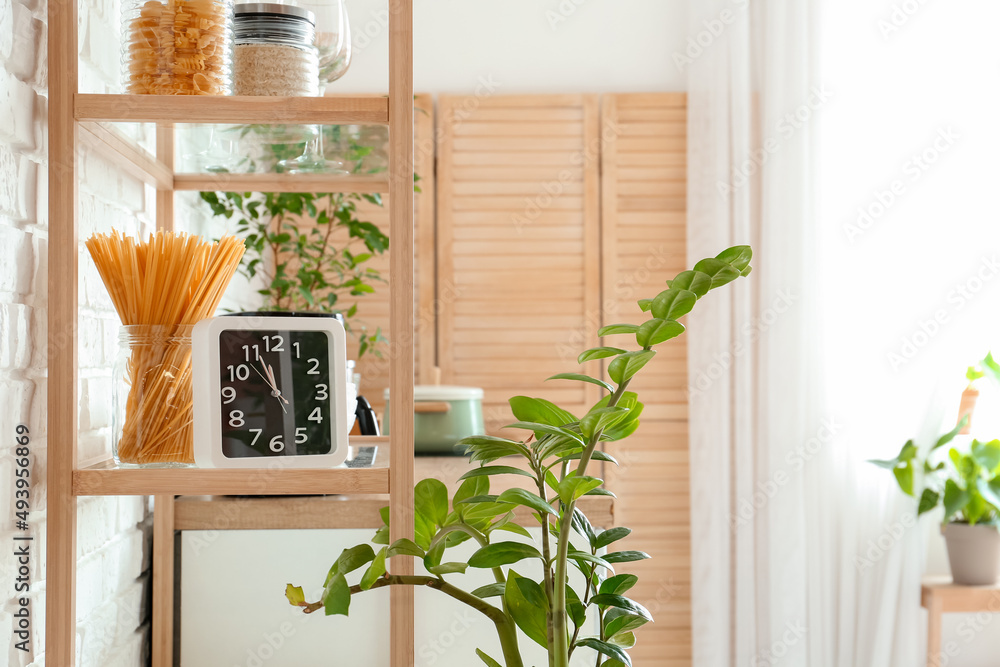 Shelving unit with clock and food in kitchen