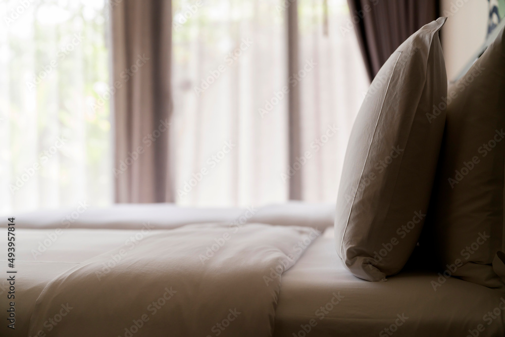 Bed maid-up with clean white pillows and bed sheets in beauty room. Close-up. Lens flair in sunlight