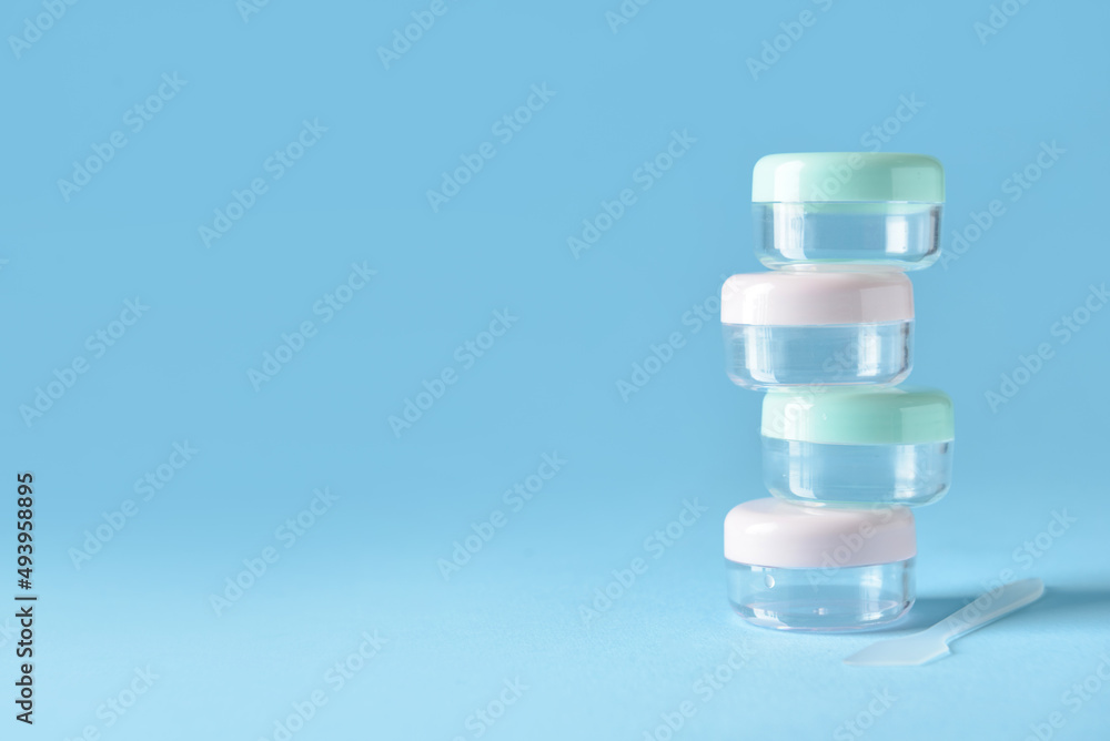 Set of empty travel cosmetic jars on blue background