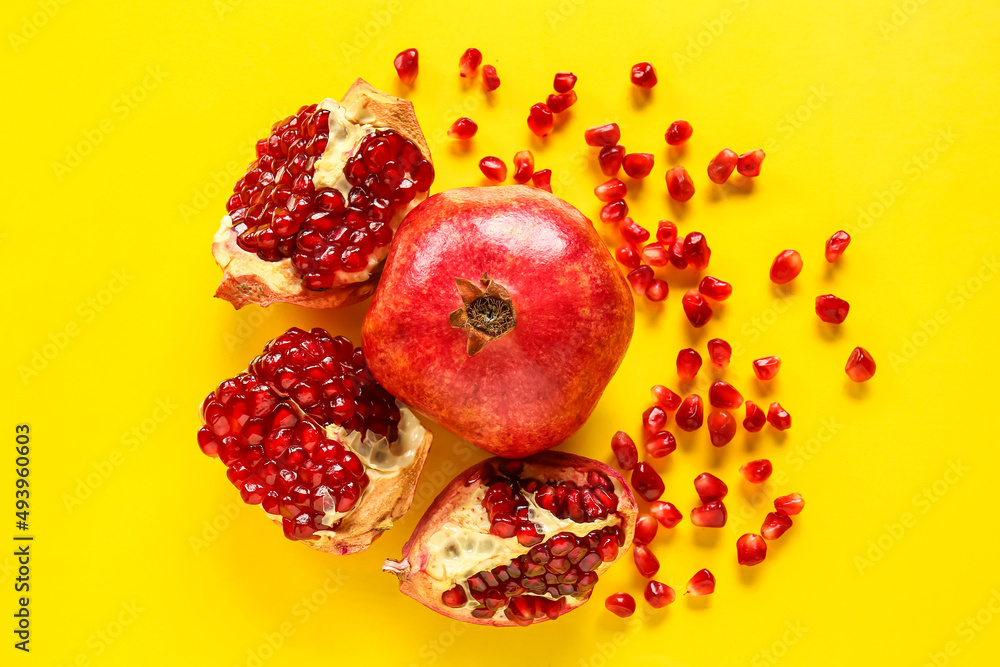 Tasty ripe pomegranate pieces on yellow background