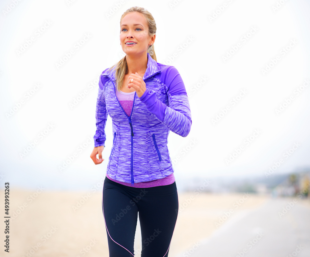 一步一步地变得更健康。一名穿着运动服的年轻女子站在海滩上的照片。