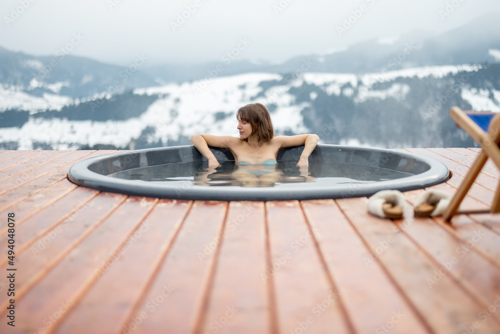 冬天，年轻女子在山上的热浴盆里洗澡。在热浴盆里休息和恢复的概念