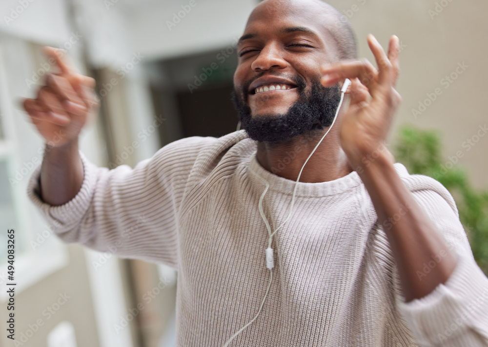 Dance breaks are essential. Shot of a young man dancing while listening to music at home.