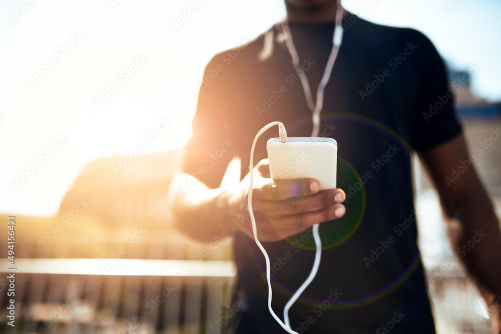 Getting into the zone with some music. Shot of a sporty young man getting his playlist ready for a r