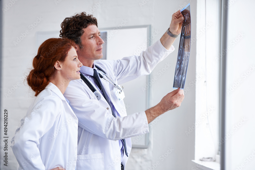 Learning something new everyday. Shot of two doctors assessing a patients x-ray at the hospital.