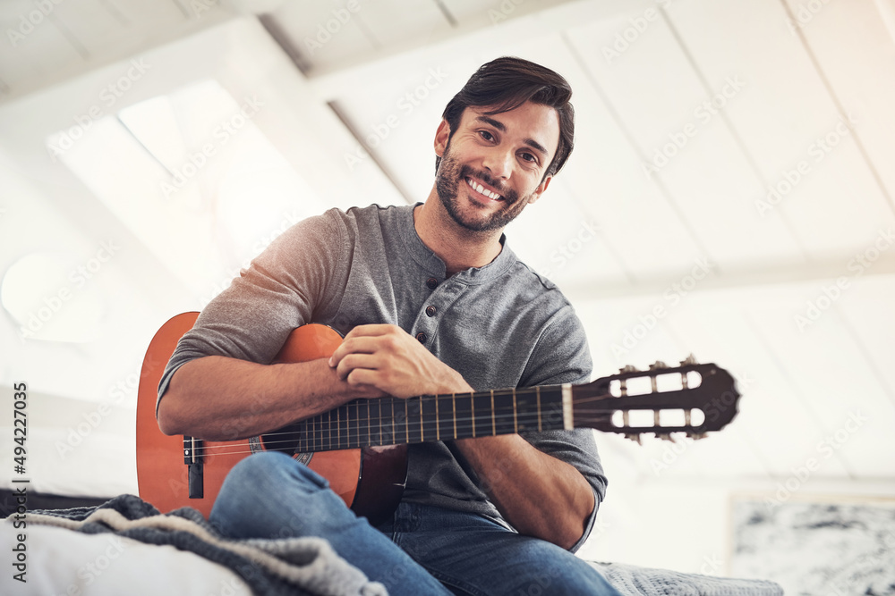 Practice makes perfect. Shot of a handsome young man practising guitar at home.