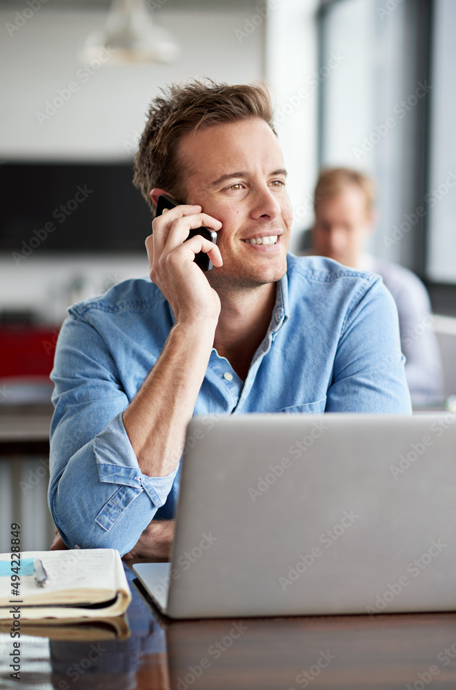 Savoring his success. Shot of a man talking on his cellphone in a casual work environment.