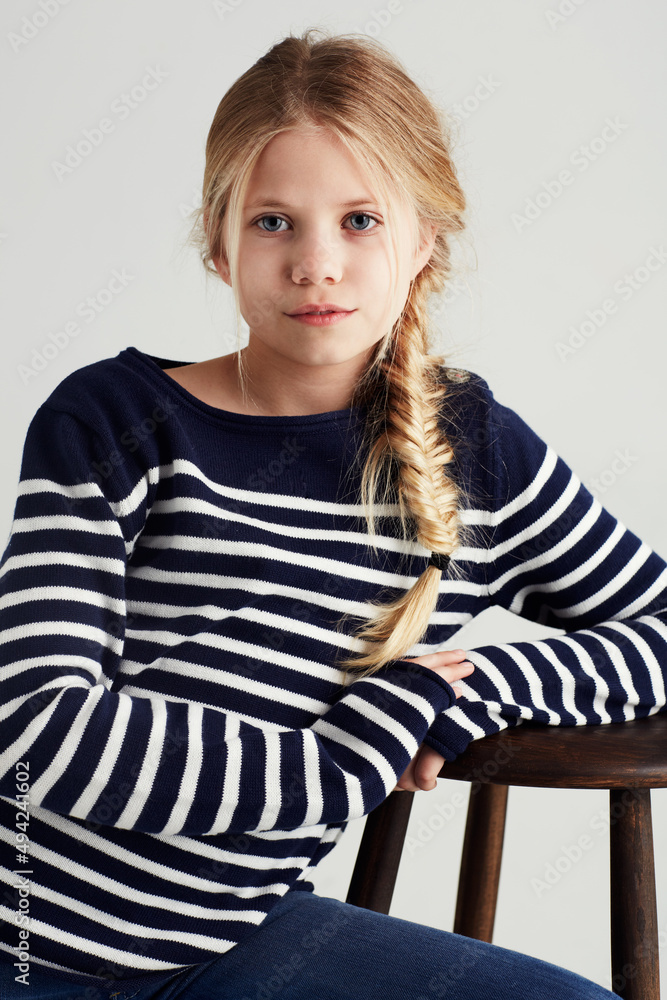 Shes got bags of attitude. Portrait of a cute girl sitting on a chair in the studio.