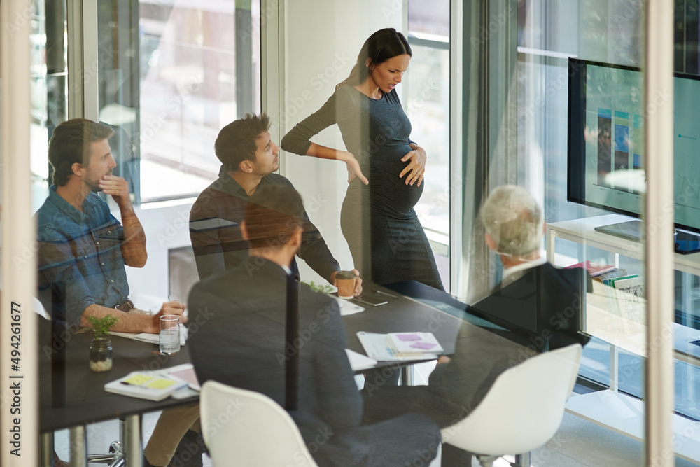 Everyone is concerned for her. Shot of a pregnant businesswoman in discomfort during a meeting.