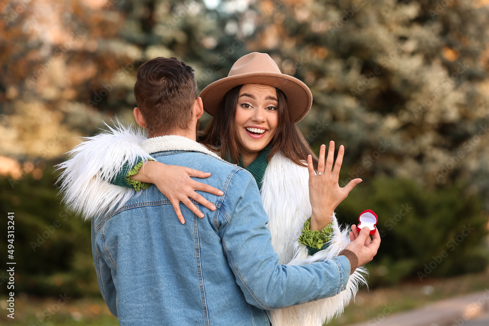 在公园求婚后，带着戒指拥抱未婚夫的快乐年轻女子