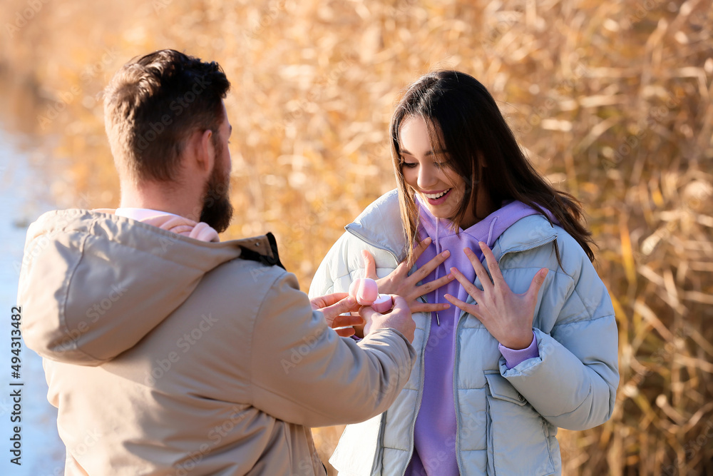 一名年轻男子在河边向他惊讶的女友求婚