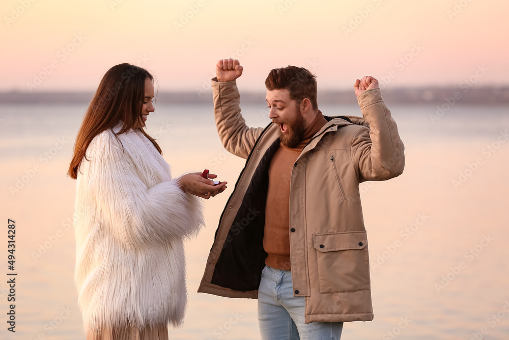 年轻女子在河边向她幸福的男友求婚