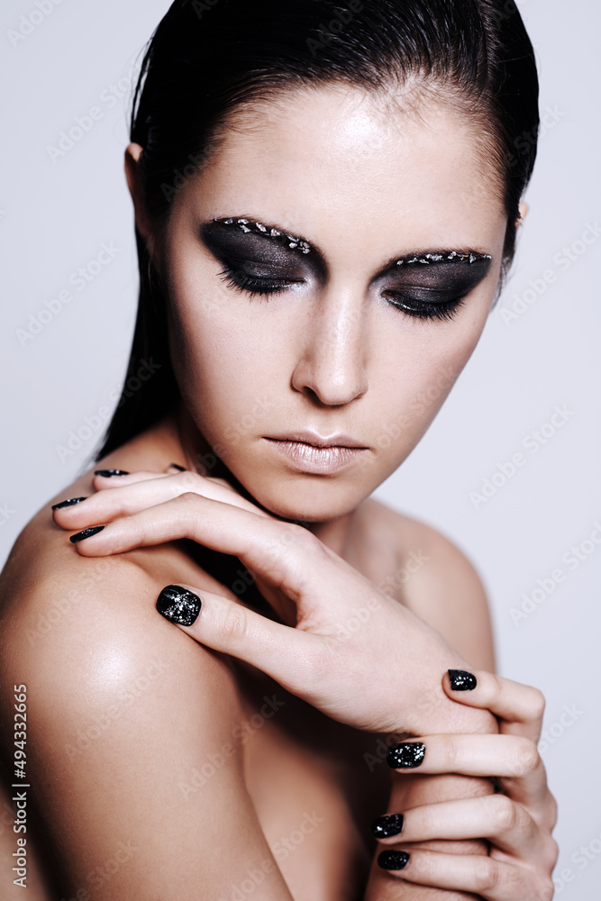 Intense beauty. Studio shot of a beautiful young woman wearing metallic-colored makeup and nail poli