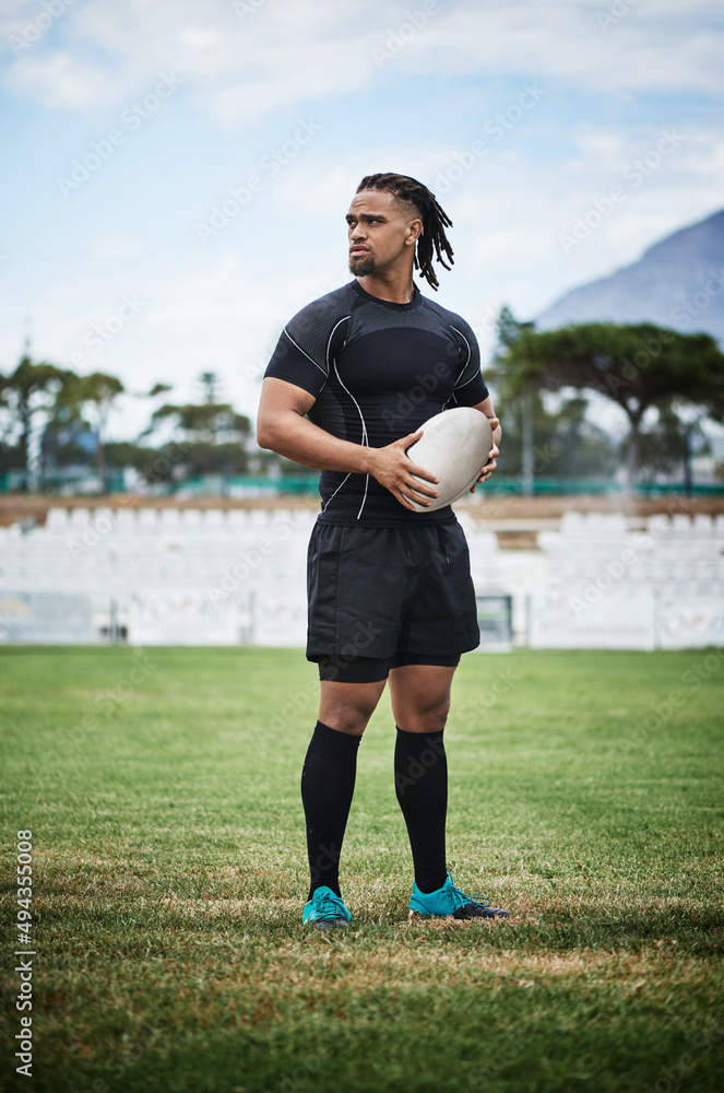 Hes the man of the game. Full length shot of a handsome young rugby player holding a rugby ball whil