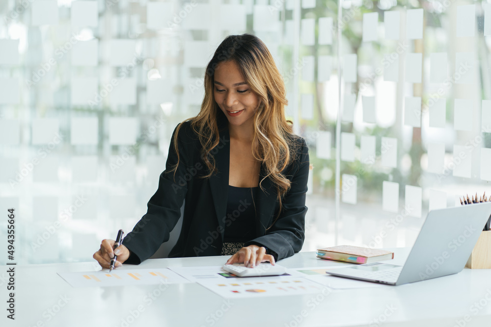 Portrait of businesswoman with laptop writes on a document at her office