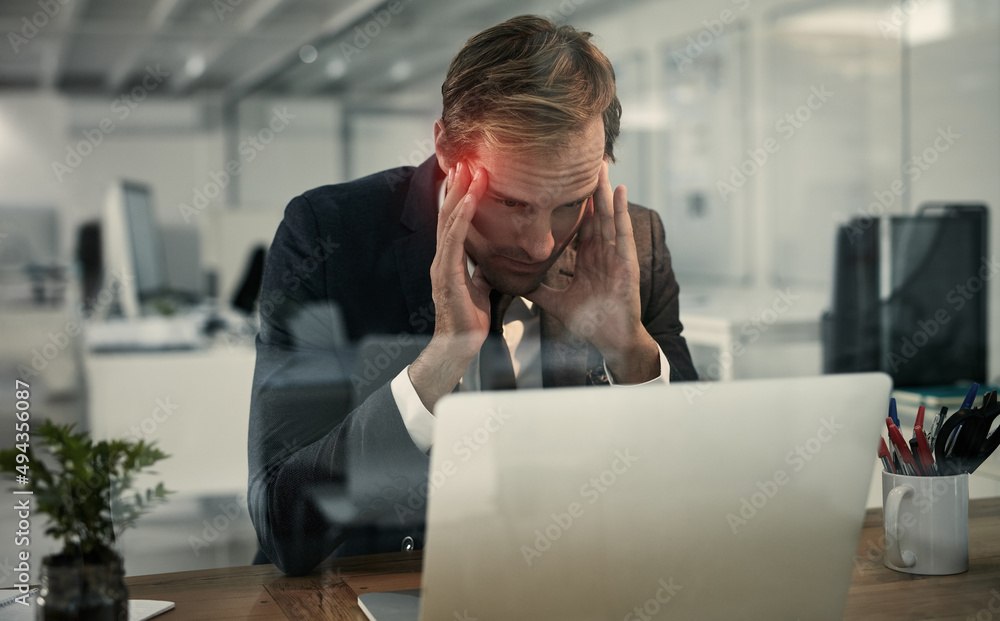 Brain overload. Shot of a businessman looking stressed while working at his laptop.